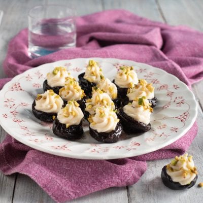 Prugne farcite con crema al mascarpone e granella di pistacchi su piatto da portata
