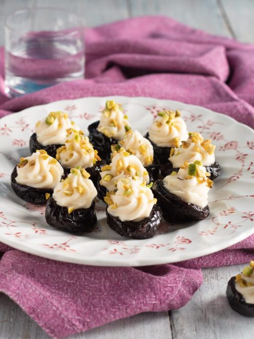 Prugne farcite con crema al mascarpone e granella di pistacchi su piatto da portata
