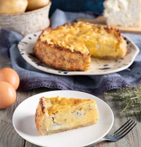 Quiche patate e gorgonzola con una fetta servita in primo piano e la torta intera sullo sfondo
