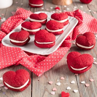 Whoopie pie red velvet a forma di cuoricino farciti con crema bianca su vassoio