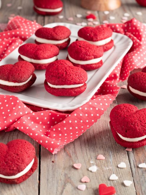 Whoopie pie red velvet a forma di cuoricino farciti con crema bianca su vassoio