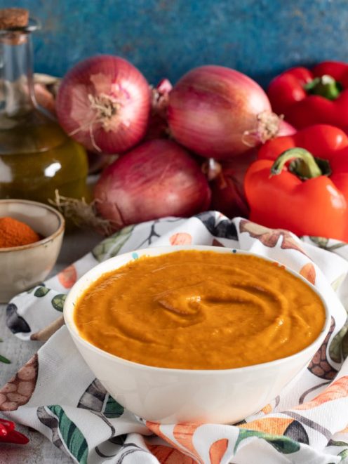 Salsa ai peperoni densa e vellutata, con cipolle rosse e peperoni freschi sullo sfondo