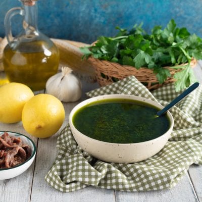 Salsa al prezzemolo densa e brillante servita con limoni, aglio e acciughe accanto
