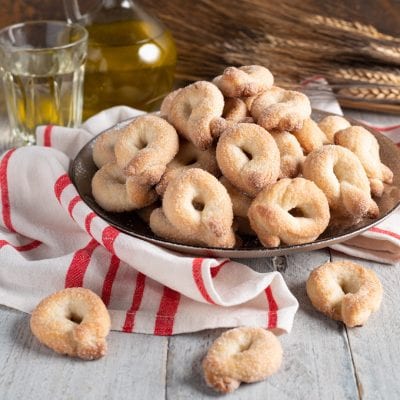 Tarallucci al vino bianco ricoperti di zucchero accatastati in un piatto colmo