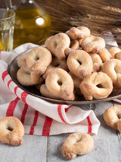 Tarallucci al vino bianco ricoperti di zucchero accatastati in un piatto colmo
