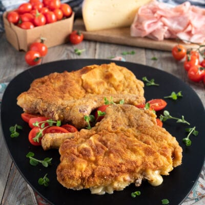 Cotolette alla valdostana impanate e filanti servite con pomodorini e maggiorana fresca