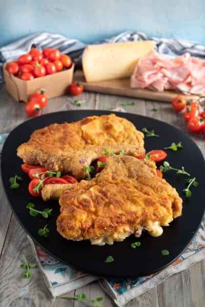 Cotolette alla valdostana impanate e filanti servite con pomodorini e maggiorana fresca