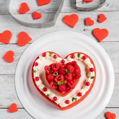 Crostata moderna a forma di cuore con crema, lamponi, ribes rosso e foglioline di menta