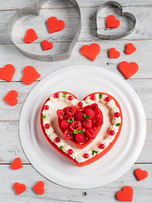 Crostata moderna a forma di cuore con crema, lamponi, ribes rosso e foglioline di menta
