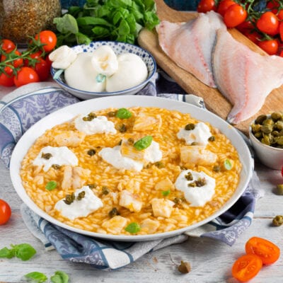 Risotto al pomodoro con orata, ciuffi di burrata, capperi e foglie di basilico fresco