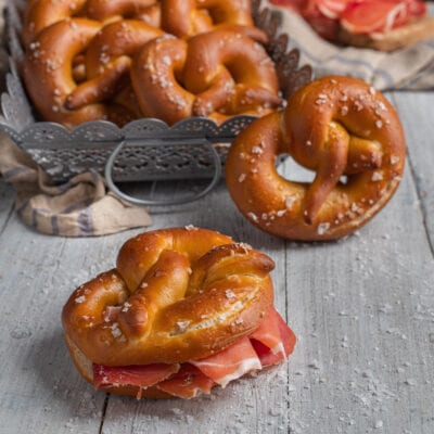Bretzel dorati con sale grosso, uno farcito con prosciutto crudo a fette