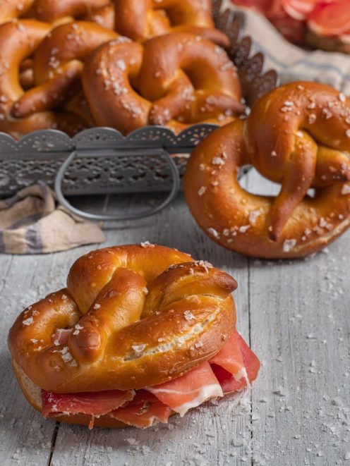 Bretzel dorati con sale grosso, uno farcito con prosciutto crudo a fette