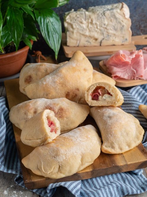 Calzoni al forno ripieni di gorgonzola e prosciutto cotto, alcuni aperti a mostrare il ripieno