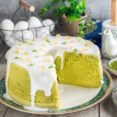 Chiffon cake al tè matcha con glassa bianca, pezzetti di zenzero candito e foglioline di menta, con una fetta rimossa
