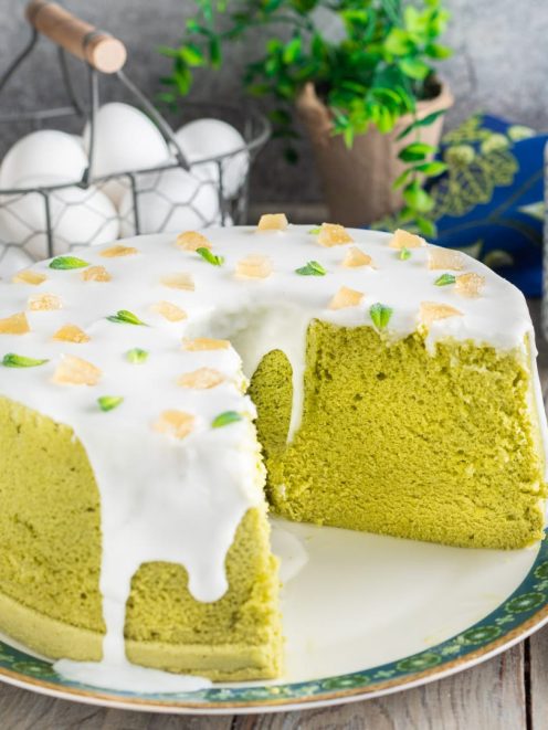 Chiffon cake al tè matcha con glassa bianca, pezzetti di zenzero candito e foglioline di menta, con una fetta rimossa