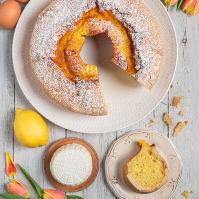 Soffione a ciambella spolverato di zucchero a velo con una fetta a mostrare la mollica soffice al limone