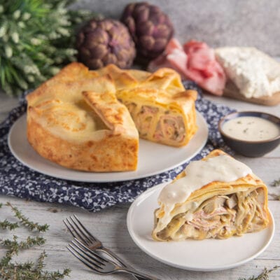 Torta di crespelle gorgonzola, prosciutto e carciofi tagliata a fette e farcita con besciamella filante