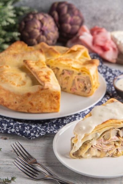 Torta di crespelle gorgonzola, prosciutto e carciofi tagliata a fette e farcita con besciamella filante