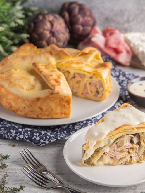 Torta di crespelle gorgonzola, prosciutto e carciofi tagliata a fette e farcita con besciamella filante