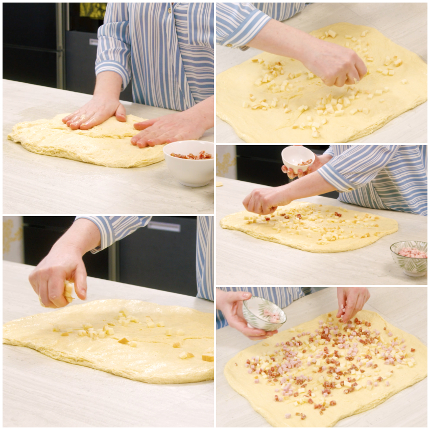 Impasto steso a rettangolo con cubetti di formaggio e salumi distribuiti sulla superficie