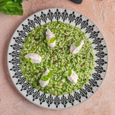Risotto verde con quenelle di ricotta e mortadella, foglie di basilico e pepe rosa
