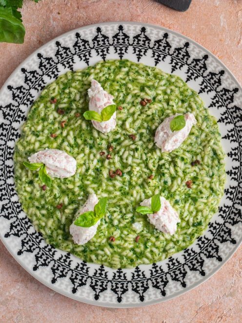 Risotto verde con quenelle di ricotta e mortadella, foglie di basilico e pepe rosa