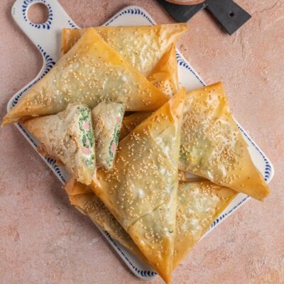 Triangoli di pasta fillo dorati con semi di sesamo, ripieni di spinaci e prosciutto cotto