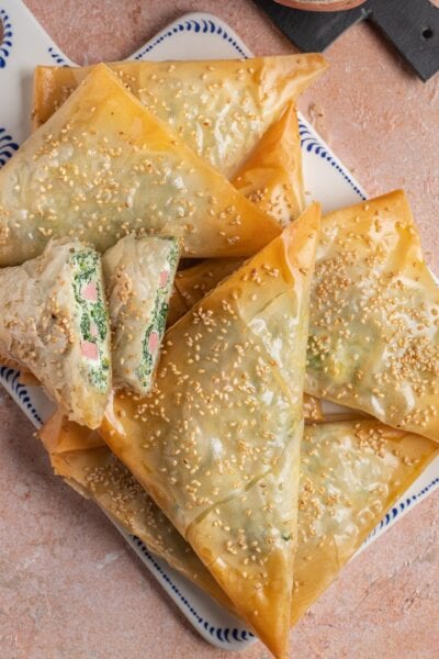 Triangoli di pasta fillo dorati con semi di sesamo, ripieni di spinaci e prosciutto cotto