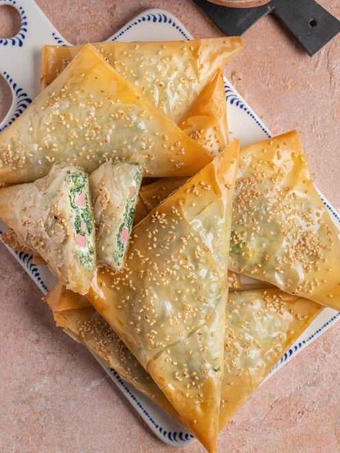 Triangoli di pasta fillo dorati con semi di sesamo, ripieni di spinaci e prosciutto cotto
