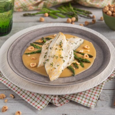 Darna di branzino su salsa dorata con asparagi verdi, nocciole tostate e timo
