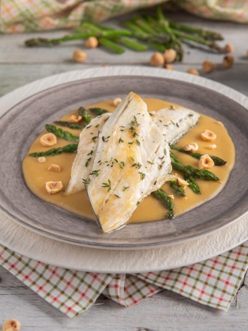 Darna di branzino su salsa dorata con asparagi verdi, nocciole tostate e timo