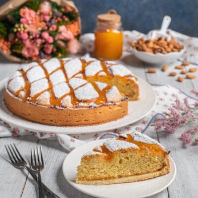 Torta Cremona con zucchero a velo e glassa all'albicocca, una fetta in primo piano che mostra la mollica dorata