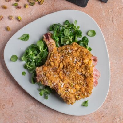 Costoletta con crosta di pistacchi e fiocchi di sale servita con valeriana fresca
