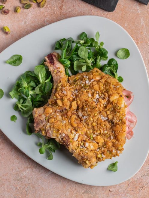 Costoletta con crosta di pistacchi e fiocchi di sale servita con valeriana fresca