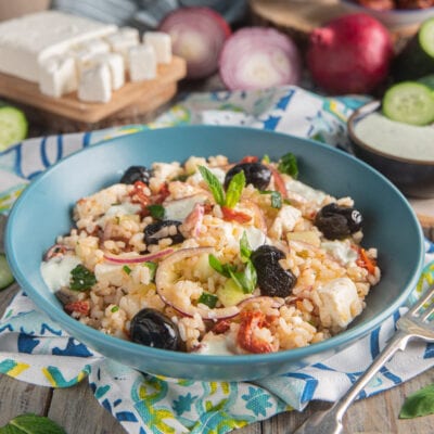 Insalata di riso alla greca con olive nere, feta, pomodori secchi, cetriolo e cipolla rossa