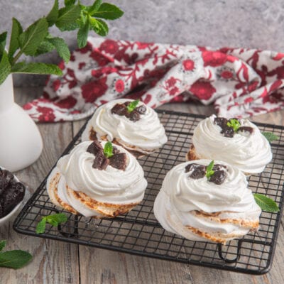 Mini pavlova con panna montata, pezzi di prugna essiccata e foglioline di menta fresca