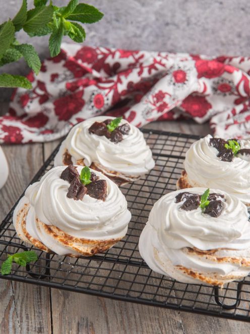 Mini pavlova con panna montata, pezzi di prugna essiccata e foglioline di menta fresca