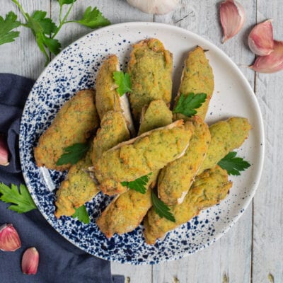 Alici ripiene con crosta verde alle erbe, guarnite con foglie di prezzemolo fresco