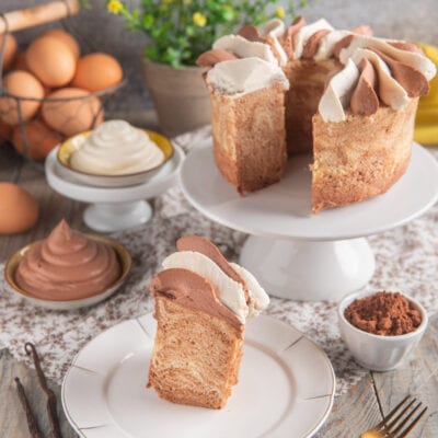 Chiffon cake marmorizzata tagliata a fetta, decorata con ciuffi di crema al cioccolato e panna