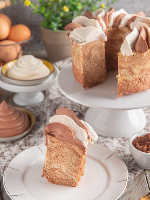 Chiffon cake marmorizzata tagliata a fetta, decorata con ciuffi di crema al cioccolato e panna