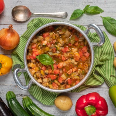 Ciabotto di verdure con pomodori, zucchine e melanzane, guarnito con foglie di basilico fresco