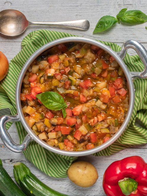 Ciabotto di verdure con pomodori, zucchine e melanzane, guarnito con foglie di basilico fresco