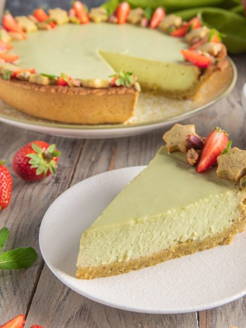Crostata fredda al pistacchio e ricotta con una fetta servita, guarnita da fragole e pistacchi