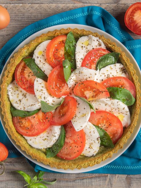 Crostata salata caprese con fette di pomodoro, mozzarella e basilico fresco a spirale