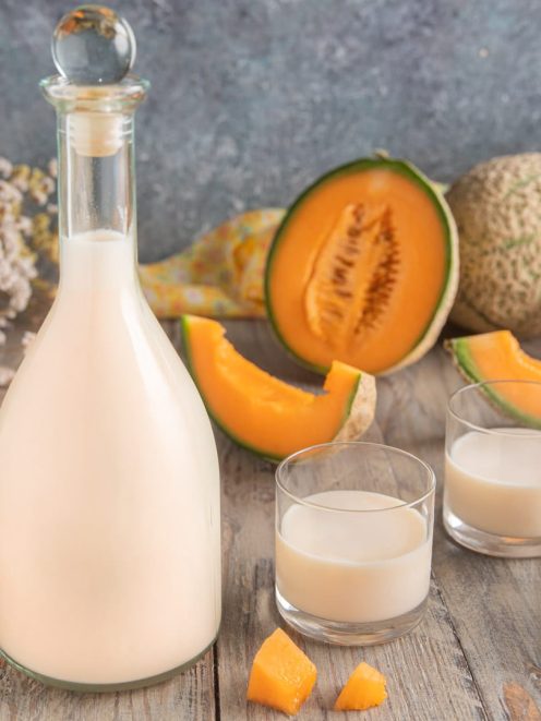 Meloncello cremoso servito in due bicchieri accanto a fette e cubetti di melone cantalupo