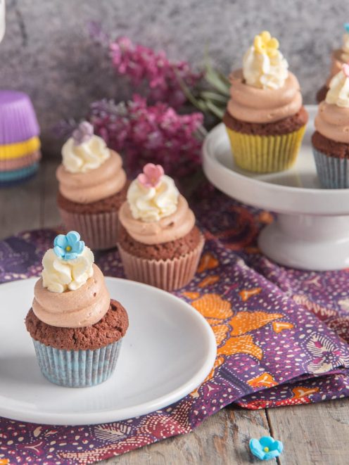 Mini cupcake ai tre cioccolati con frosting rosa e fiori di zucchero colorati