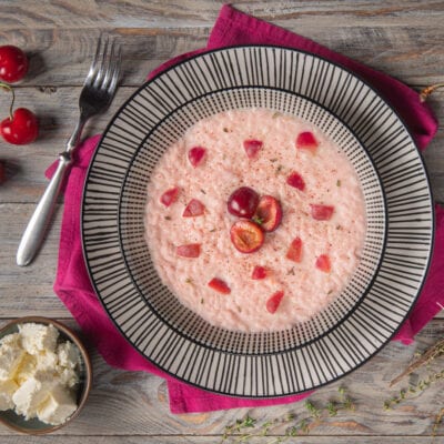 Risotto alle ciliegie e robiola con pezzi di frutta fresca e una spolverata di spezie