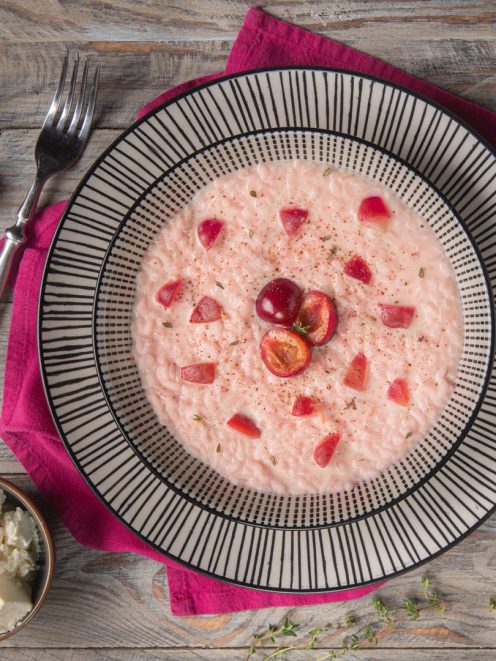 Risotto alle ciliegie e robiola con pezzi di frutta fresca e una spolverata di spezie