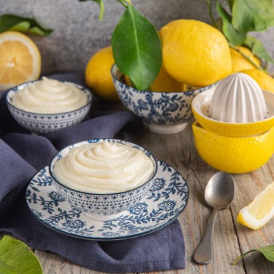 Crema al limone senza uova servita in ciotoline, con limoni freschi sullo sfondo