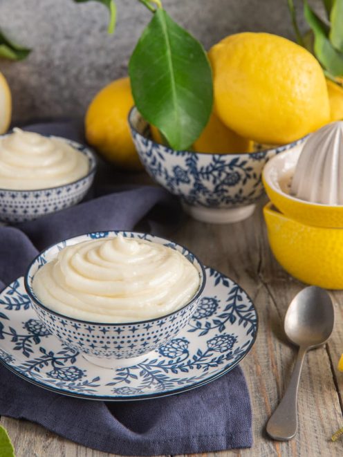 Crema al limone senza uova servita in ciotoline, con limoni freschi sullo sfondo